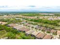 Expansive aerial view of a residential neighborhood with lush greenery and a glimpse of a community pond at 5416 Hope Sound Cir, Sarasota, FL 34238