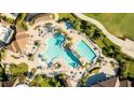 Aerial view of a community pool area featuring multiple pools, lush landscaping, and lounge chairs for relaxing at 5811 Brandon Run, Bradenton, FL 34211