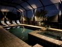 Inviting screened-in pool and spa area featuring lounge chairs and lush tropical landscaping at night at 5917 Cessna Run, Lakewood Ranch, FL 34211