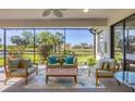 Screened patio with comfortable seating, a ceiling fan, and a view of the serene lake and lush landscaping at 6458 Tailfeather Way, Bradenton, FL 34203