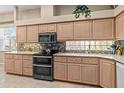 Well-lit kitchen showcases wooden cabinetry, mosaic tile backsplash, and modern stainless steel appliances at 686 Silk Oak Dr, Venice, FL 34293
