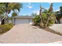 Paver driveway leads to a two-car garage, complemented by lush landscaping at 711 Birdsong Ln, Sarasota, FL 34242