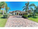 Beautiful single Gathering home showcasing a brick paver driveway, manicured lawn and tropical landscaping at 13107 Bridgeport Xing, Lakewood Ranch, FL 34211