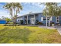 Inviting single-story light blue home featuring a lush lawn and a quaint, welcoming entrance at 1320 Magellan Dr, Sarasota, FL 34243