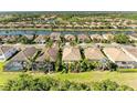 Aerial view of a waterfront community featuring tile roofs, lush landscaping, and a serene lake at 135 River Enclave Ct, Bradenton, FL 34212