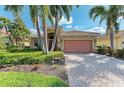 Charming single-story home featuring a tile roof, brick driveway, and tropical landscaping at 135 River Enclave Ct, Bradenton, FL 34212