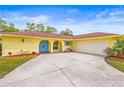 Lovely yellow home featuring a two car garage, beautiful landscaping, and a bright blue front door and shutters at 2909 Concord St, Sarasota, FL 34231