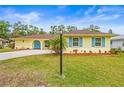Well-maintained single-story home with lush green lawn, bright blue shutters, and a yellow facade at 2909 Concord St, Sarasota, FL 34231