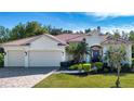 Inviting single-story home with a brick driveway, three-car garage, and vibrant landscaping at 349 Blackbird Ct, Bradenton, FL 34212