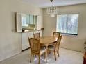 Cozy dining area showcasing a wooden table set, chandelier, and a window with views of lush scenery at 3500 El Conquistador Pkwy # 129, Bradenton, FL 34210