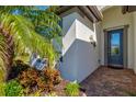 Inviting entryway with a decorative glass door, brick pavers, and lush tropical landscaping at 5590 Rain Lily Ct, Sarasota, FL 34238