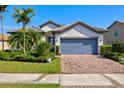 Charming single-story home featuring a tile roof, manicured landscaping, and a brick paver driveway at 5590 Rain Lily Ct, Sarasota, FL 34238