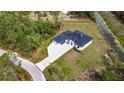 Aerial view of a modern home with a long driveway, black roof, surrounded by lush greenery and a canal at 5792 Nymph Ave, North Port, FL 34288
