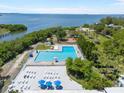 Aerial view of a community pool featuring lounge chairs, picnic tables, and views of the bay at 6715 Georgia Ave, Bradenton, FL 34207