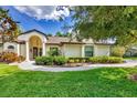 Beautiful home with lush green grass, mature trees, and lovely landscaping and a covered front entrance at 8161 Shadow Pine Way, Sarasota, FL 34238