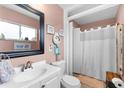 Clean and functional bathroom with a white sink, toilet, framed mirror and shower at 8718 Gaillard Ave, North Port, FL 34287