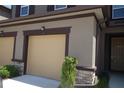 Two car garage on a tan house with brown trim and stone accent with well kept bushes at 11828 Sky Acres Ter, Bradenton, FL 34211