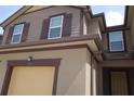 Close-up of the exterior of a two-story townhouse featuring brown trim and a tan garage door at 11828 Sky Acres Ter, Bradenton, FL 34211