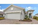 Home exterior showcasing a gray facade, two-car garage, and a brick-paved driveway at 12520 Brookgreen St, Venice, FL 34293