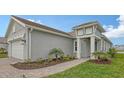 Gray home exterior featuring manicured landscaping, blue door, and tile roof at 12520 Brookgreen St, Venice, FL 34293