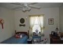 Comfortable bedroom showcasing twin bed, window with lace curtains, and ceiling fan with light fixture at 1711 30Th W St, Bradenton, FL 34205
