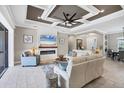 Comfortable living room features an elegant tray ceiling, recessed lighting, fireplace, and plush seating at 27454 Hole In One Pl, Englewood, FL 34223