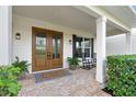 Inviting front porch with double doors, brick flooring, rocking chairs, and manicured greenery at 30416 Saddlebag Trl, Myakka City, FL 34251
