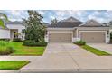 Attached two car garage of a well-maintained tan and white home with nicely manicured landscaping at 4021 Wildgrass Pl, Parrish, FL 34219