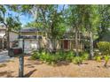 Inviting two-story home with a front porch and a two-car garage, surrounded by mature trees and lush landscaping at 4063 Woodview Dr, Sarasota, FL 34232