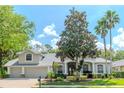 Inviting single-story home featuring mature landscaping, a two-car garage, and a charming covered entryway at 5151 Jasmine Way, Palm Harbor, FL 34685