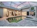 Covered pool area featuring brick pavers, a hot tub, and access to multiple rooms in the house at 5151 Jasmine Way, Palm Harbor, FL 34685