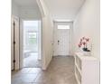 Bright hallway featuring neutral tile flooring and a view into a well-lit bedroom at 5688 Woodland Sage Dr, Sarasota, FL 34238