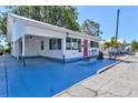 Exterior view of cozy home featuring a bright pink door, blue painted driveway, and lush landscaping at 7 Braden Castle Dr, Bradenton, FL 34208