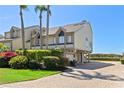 Coastal townhome features lush landscaping, brick paver driveway, and desirable under-house garage and parking at 71 Tidy Island Blvd, Bradenton, FL 34210
