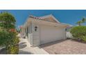 Charming home with a two-car garage and brick paved driveway lined with lush landscaping at 7664 Camminare Dr, Sarasota, FL 34238