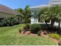 Landscaped front yard features mulch, flowers, palm trees, and green grass at 12272 Stuart Dr, Venice, FL 34293