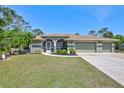 Charming home with manicured lawn, arched entryway, three-car garage, and lush tropical landscaping at 15107 3Rd E Dr, Bradenton, FL 34212