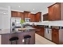 Modern kitchen with cherry wood cabinets, granite countertops, stainless steel appliances, and island seating at 4107 Pine Meadow Dr, Parrish, FL 34219