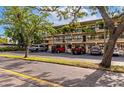 Exterior shot of condos with a parking lot with several parked vehicles with palm trees and shade trees at 425 30Th W Ave # C208, Bradenton, FL 34205