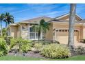 Beautiful exterior with stone accents, a well-manicured lawn, tropical landscaping, and a paver driveway, creating a welcoming curb appeal at 4250 Turnberry Cir, North Port, FL 34288