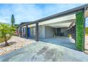 Attached carport area features a finished concrete floor and a decorative privacy wall, enhancing the home's exterior at 4409 Maceachen Blvd, Sarasota, FL 34233