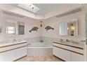 Luxurious bathroom featuring double sinks, a soaking tub, tile flooring, and a unique skylight with decorative accents at 4655 Payne St, North Port, FL 34287