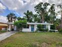 Charming one-story home featuring a bright blue door, manicured landscaping, and a welcoming entrance at 4712 Cronin Dr, Sarasota, FL 34232