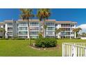 Beautiful condo exterior featuring a well-maintained lawn, mature palm trees, and private balcony at 605 Sutton Pl # 401-A, Longboat Key, FL 34228