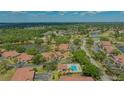 Expansive aerial view showcasing a community, pools, and a serene lake against a backdrop of verdant trees at 7269 Golf Pointe Way, Sarasota, FL 34243