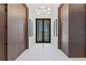 Bright foyer featuring marble floors, striking light fixture, and paneled walls leading to double doors with waterfront view at 800 Blue Shell Loop, Sarasota, FL 34240
