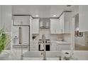 Modern kitchen featuring white cabinets, stainless steel appliances, stylish backsplash, and a farmhouse sink at 8419 Sylvan Woods Dr, Sarasota, FL 34243