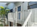 Charming front entrance with a blue door, white railing, and tropical landscaping at 1233 Dockside Pl # 207, Sarasota, FL 34242