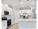 Modern kitchen boasts white cabinets, stainless steel appliances, and a spacious center island with pendant lighting at 1596 Laurel Brook Ln, Port Charlotte, FL 33953