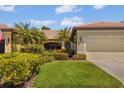 Charming one-story house with lush landscaping, swaying palms, well manicured lawn and a tile roof at 2064 Batello Dr, Venice, FL 34292